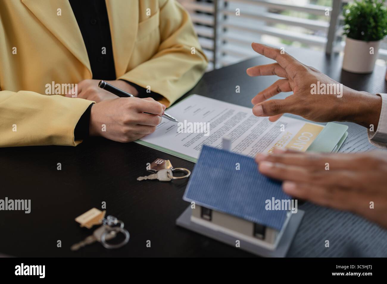 un agente immobiliare sta spiegando i dettagli di un contratto di acquisto di una casa a un acquirente, gli sta dicendo che si tratta di un investimento, di un bene immobile, Foto Stock