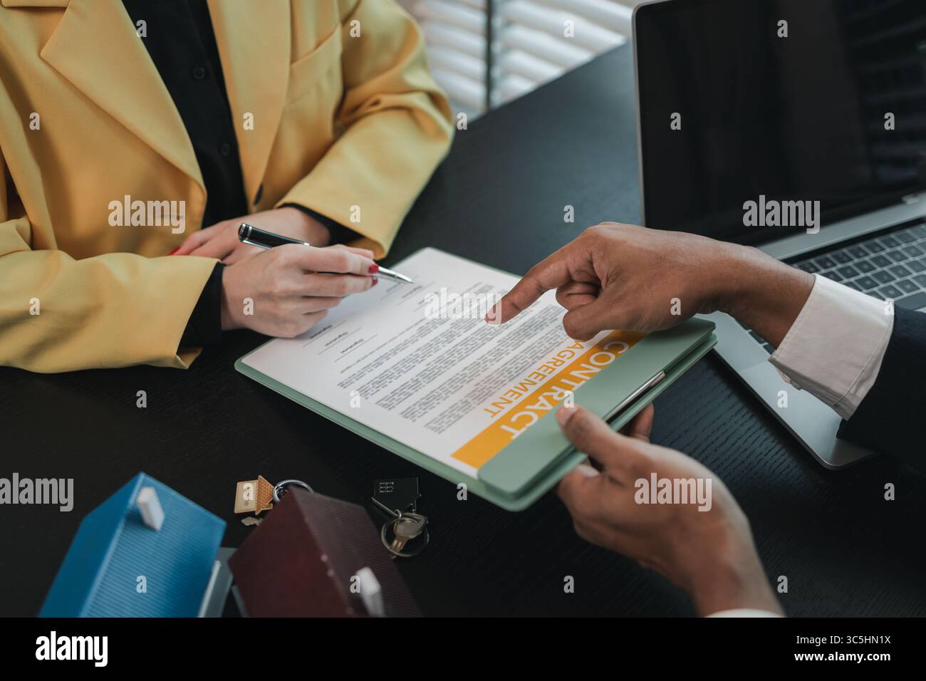 un agente immobiliare sta spiegando i dettagli di un contratto di acquisto di una casa a un acquirente, gli sta dicendo che si tratta di un investimento, di un bene immobile, Foto Stock