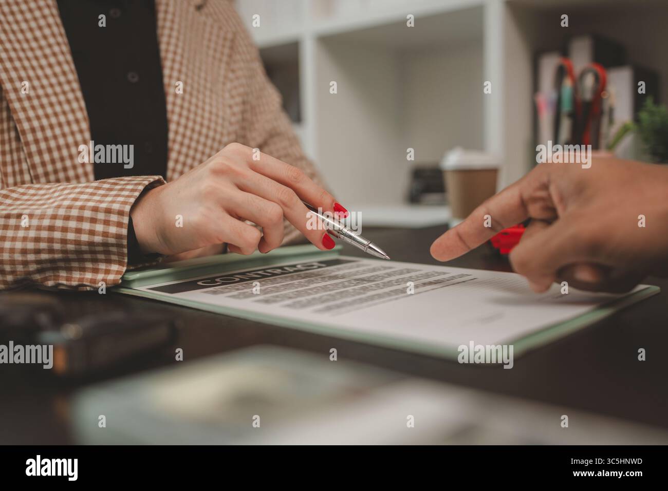 un venditore di auto sta spiegando i dettagli di un contratto di acquisto di un'auto all'acquirente prima di firmare il contratto di vendita, lo showroom, il concessionario, il contratto auto, Foto Stock