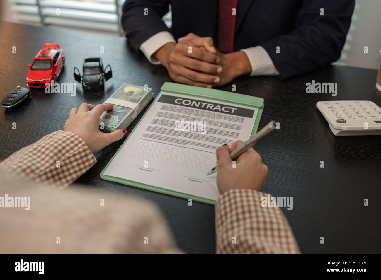 un venditore di auto sta spiegando i dettagli di un contratto di acquisto di un'auto all'acquirente prima di firmare il contratto di vendita, lo showroom, il concessionario, il contratto auto, Foto Stock