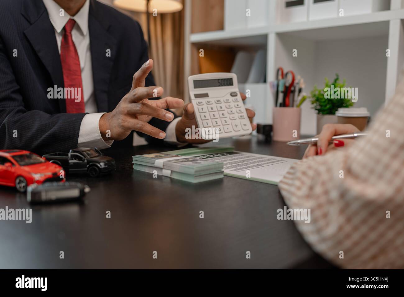 un venditore di auto sta spiegando i dettagli di una vettura e il prezzo a cui un acquirente è interessato, il responsabile vendite dello showroom ha spiegato la quantità di int Foto Stock