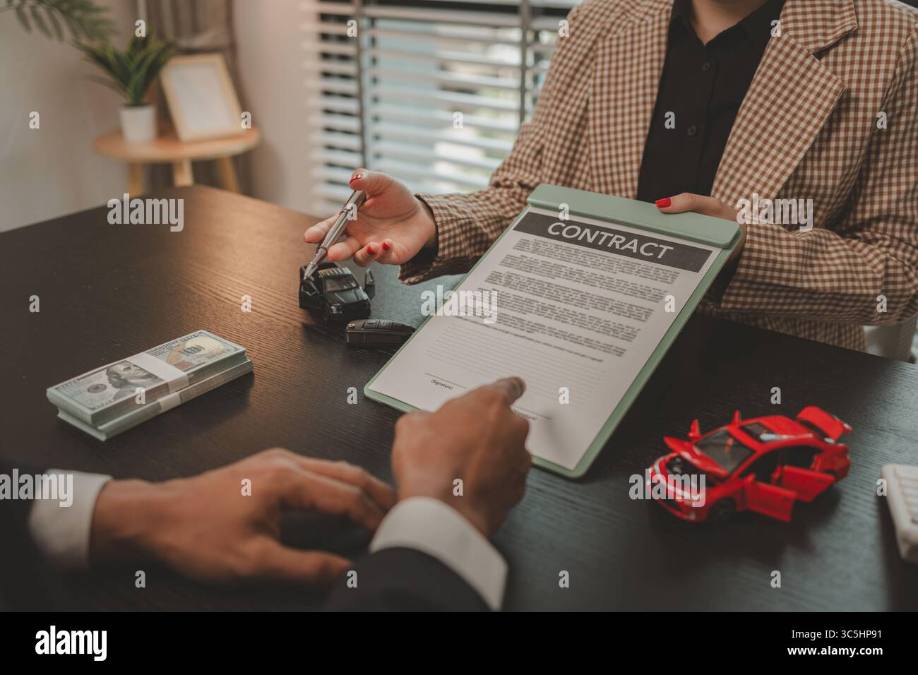 un venditore di auto sta spiegando i dettagli di un contratto di acquisto di un'auto all'acquirente prima di firmare il contratto di vendita, lo showroom, il concessionario, il contratto auto, Foto Stock