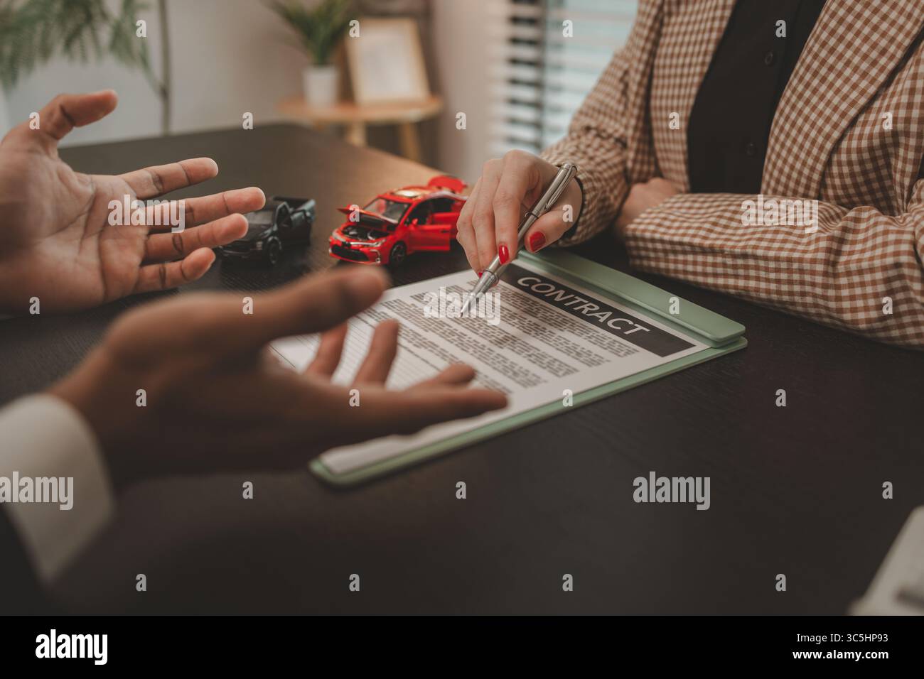 un venditore di auto sta spiegando i dettagli di un contratto di acquisto di un'auto all'acquirente prima di firmare il contratto di vendita, lo showroom, il concessionario, il contratto auto, Foto Stock