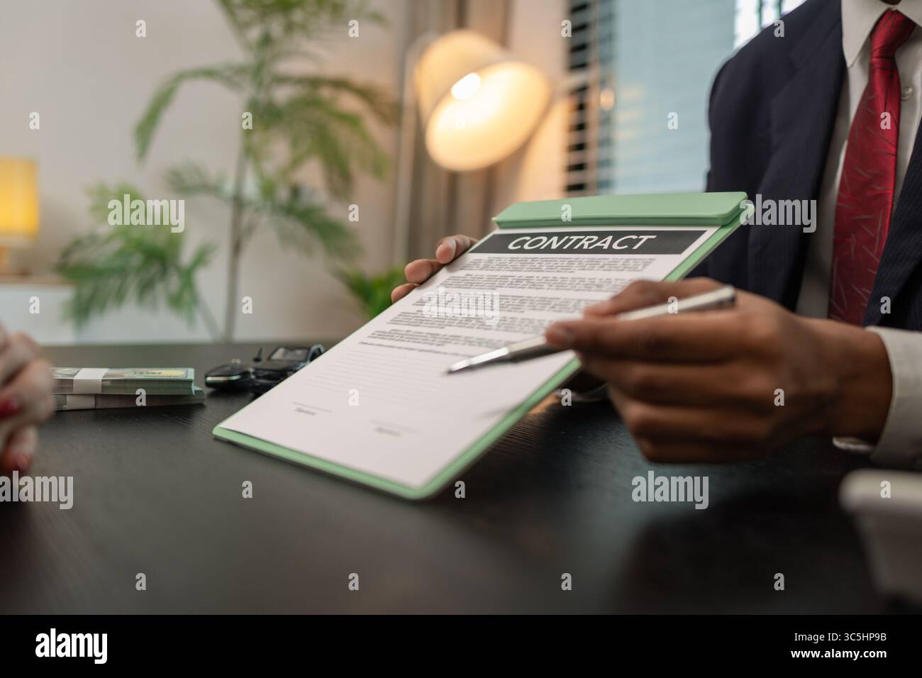 un venditore di auto sta spiegando i dettagli di un contratto di acquisto di un'auto all'acquirente prima di firmare il contratto di vendita, lo showroom, il concessionario, il contratto auto, Foto Stock
