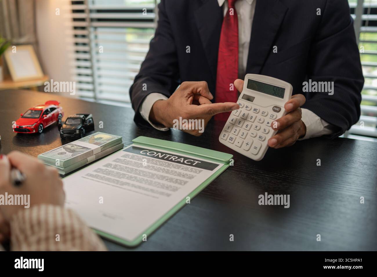 un venditore di auto sta spiegando i dettagli di una vettura e il prezzo a cui un acquirente è interessato, il responsabile vendite dello showroom ha spiegato la quantità di int Foto Stock