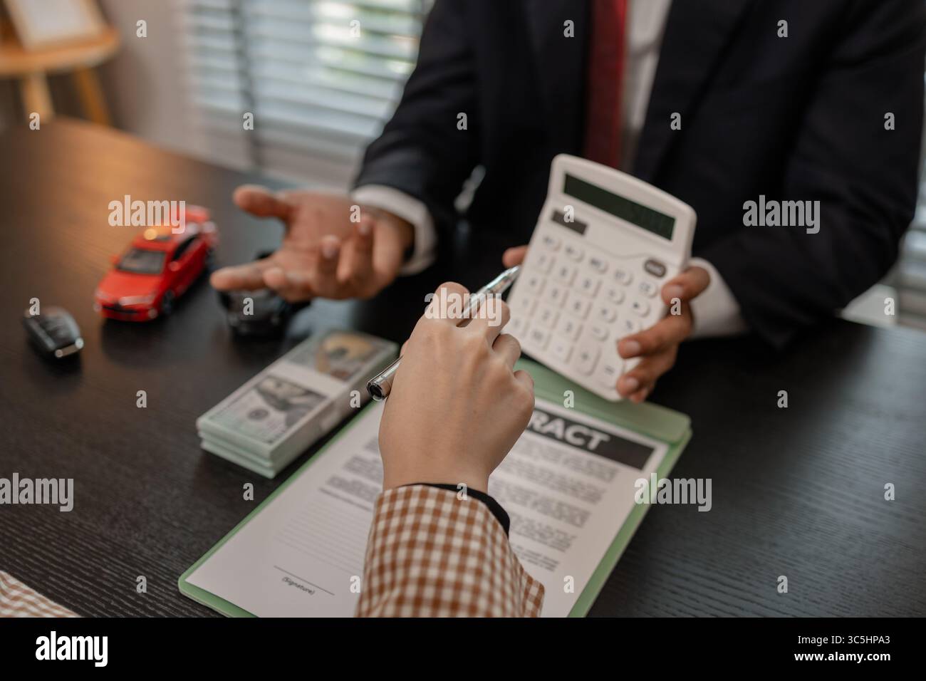 un venditore di auto sta spiegando i dettagli di una vettura e il prezzo a cui un acquirente è interessato, il responsabile vendite dello showroom ha spiegato la quantità di int Foto Stock