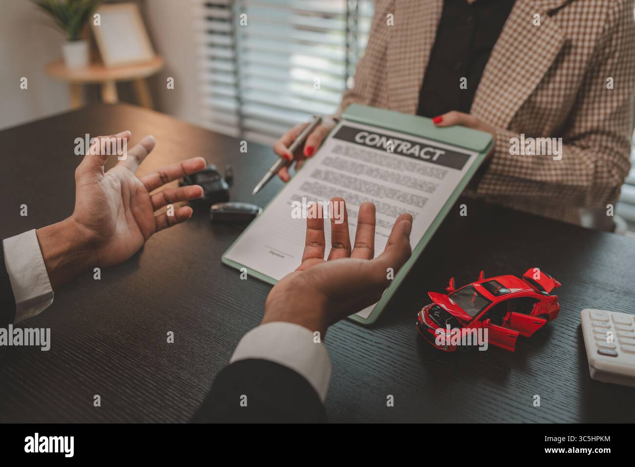 un venditore di auto sta spiegando i dettagli di un contratto di acquisto di un'auto all'acquirente prima di firmare il contratto di vendita, lo showroom, il concessionario, il contratto auto, Foto Stock