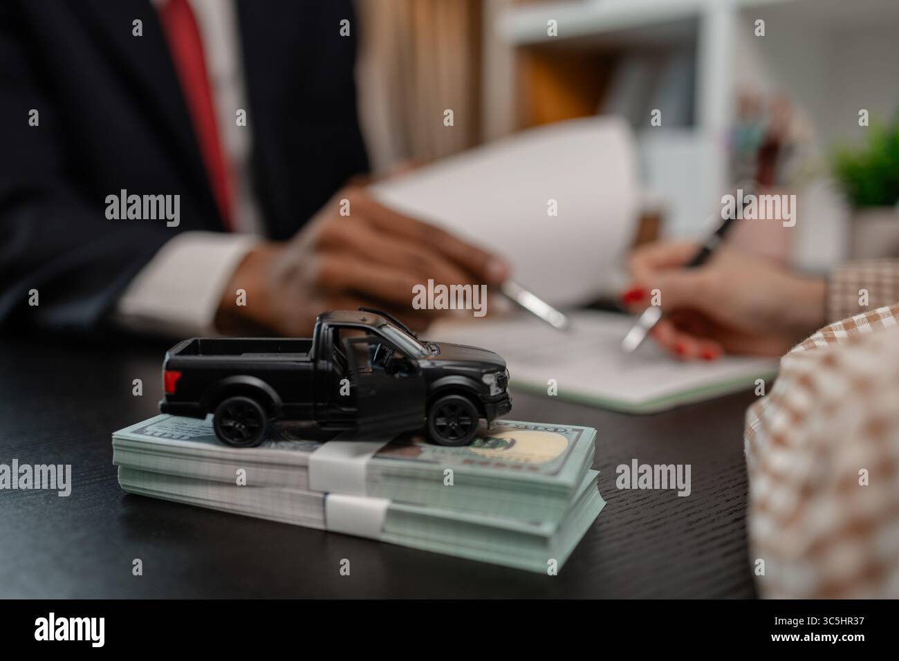 un venditore di auto sta spiegando i dettagli di un contratto di acquisto di un'auto all'acquirente prima di firmare il contratto di vendita, lo showroom, il concessionario, il contratto auto, Foto Stock