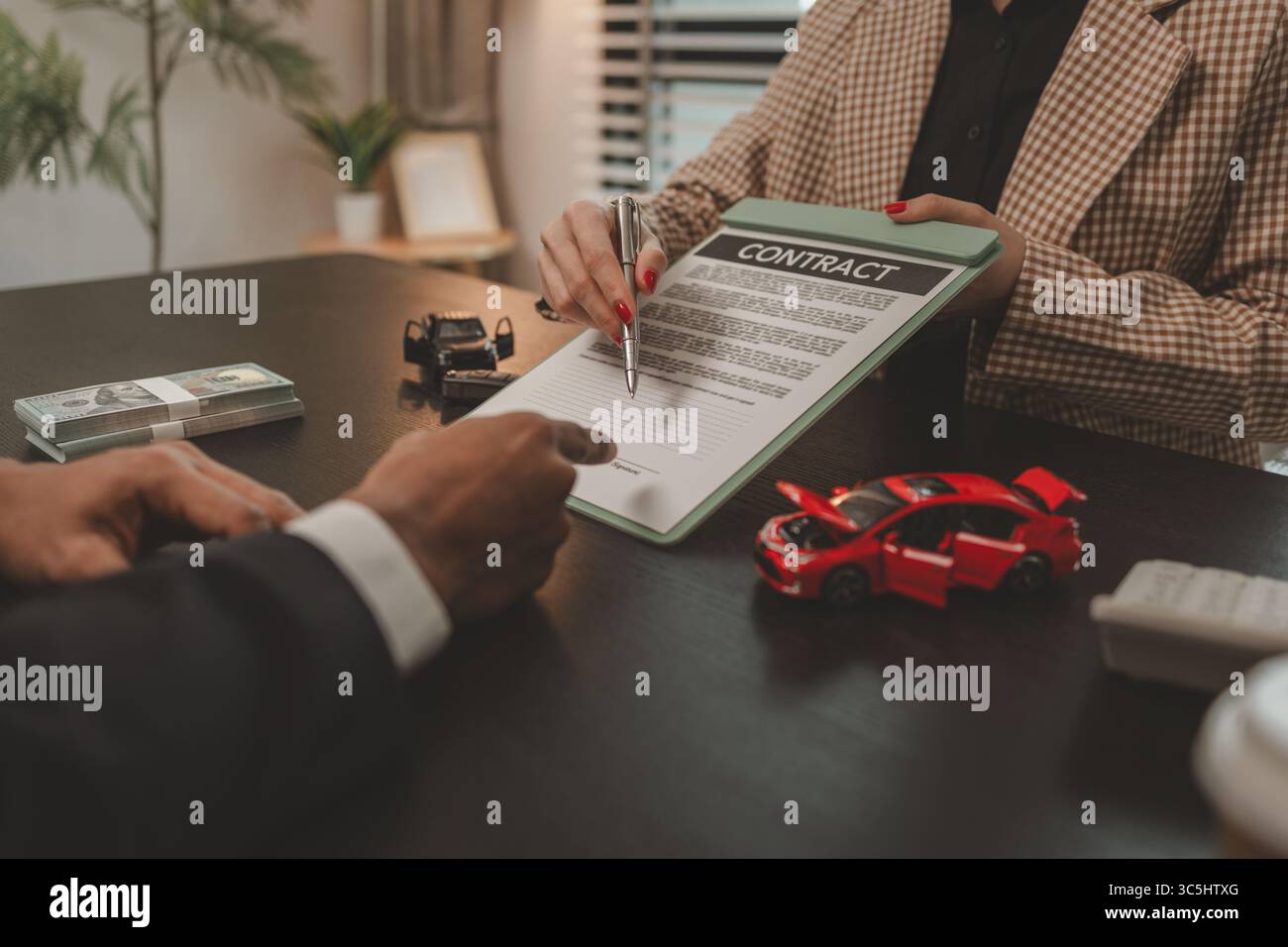 un venditore di auto sta spiegando i dettagli di un contratto di acquisto di un'auto all'acquirente prima di firmare il contratto di vendita, lo showroom, il concessionario, il contratto auto, Foto Stock