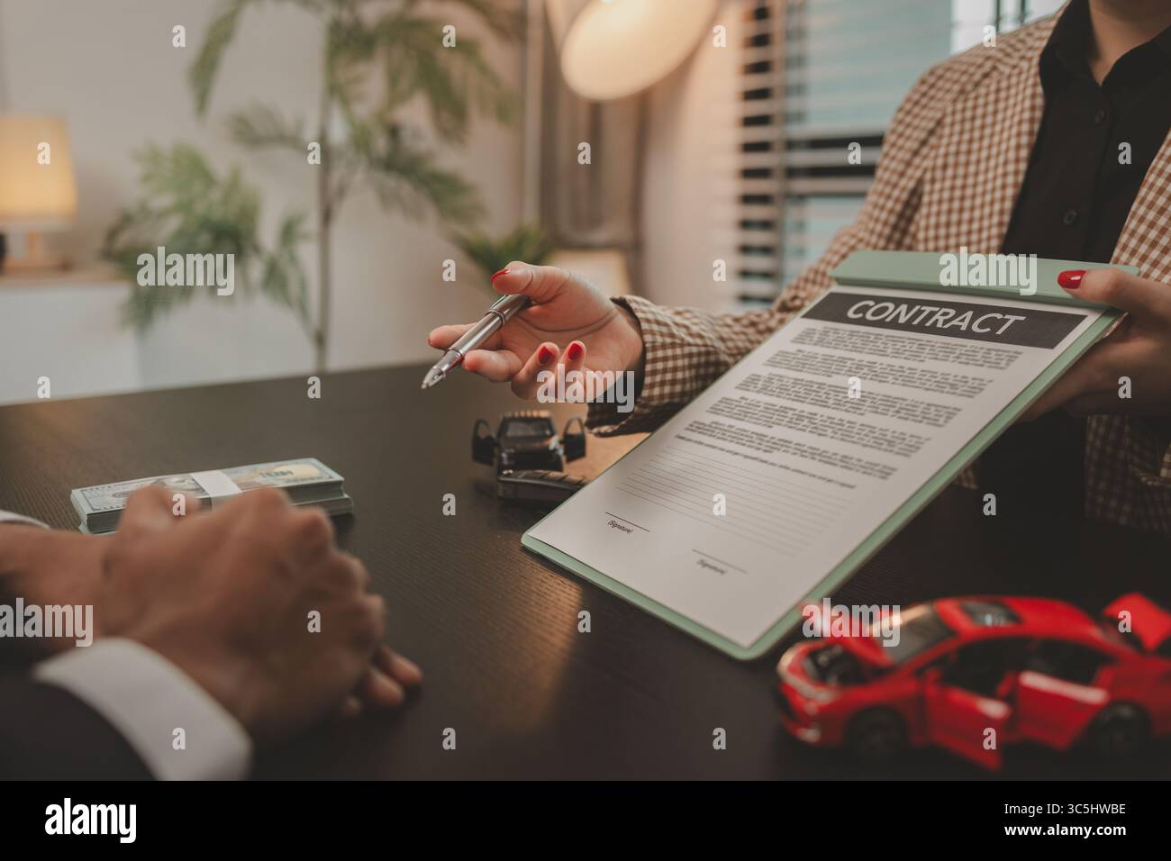 un venditore di auto sta spiegando i dettagli di un contratto di acquisto di un'auto all'acquirente prima di firmare il contratto di vendita, lo showroom, il concessionario, il contratto auto, Foto Stock