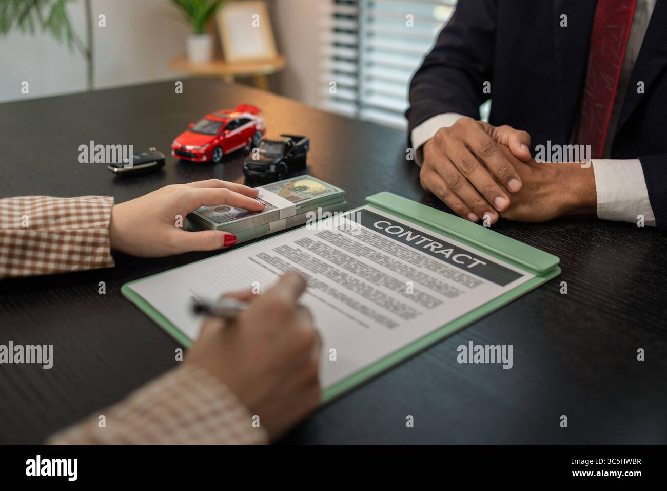 un venditore di auto sta spiegando i dettagli di un contratto di acquisto di un'auto all'acquirente prima di firmare il contratto di vendita, lo showroom, il concessionario, il contratto auto, Foto Stock