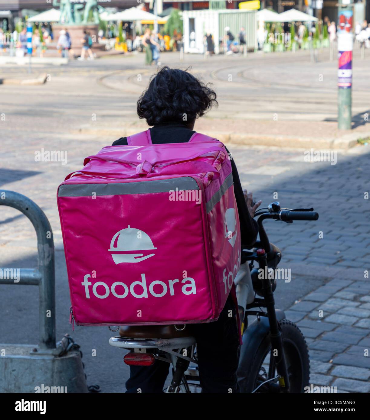 Un corriere Foodora che aspetta al semaforo di Mannerheimintie. Foto Stock