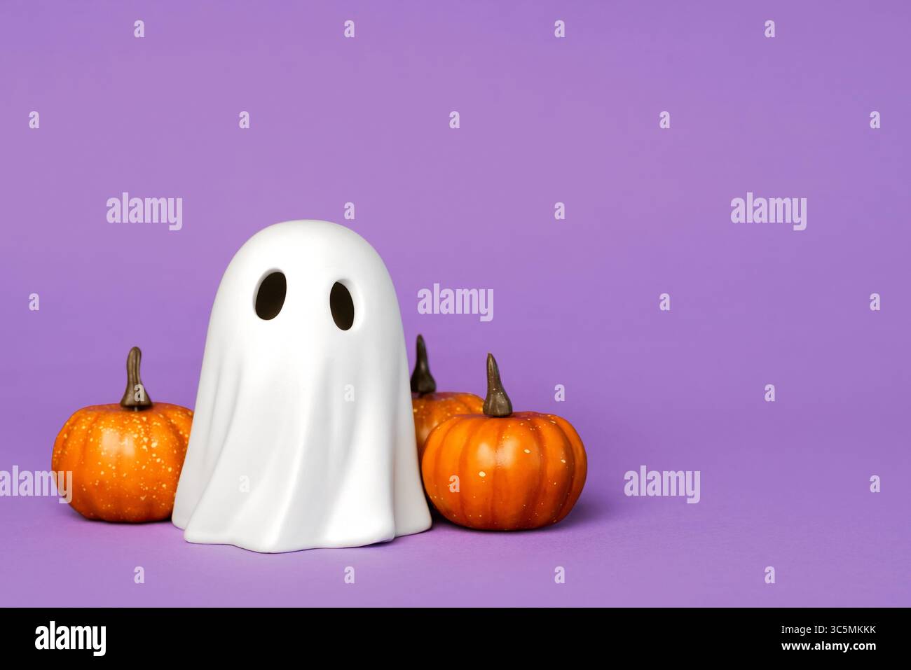 Divertente fantasma di Halloween con zucche di Halloween con spazio per testo su sfondo viola. Sfondo del concetto di Halloween Foto Stock
