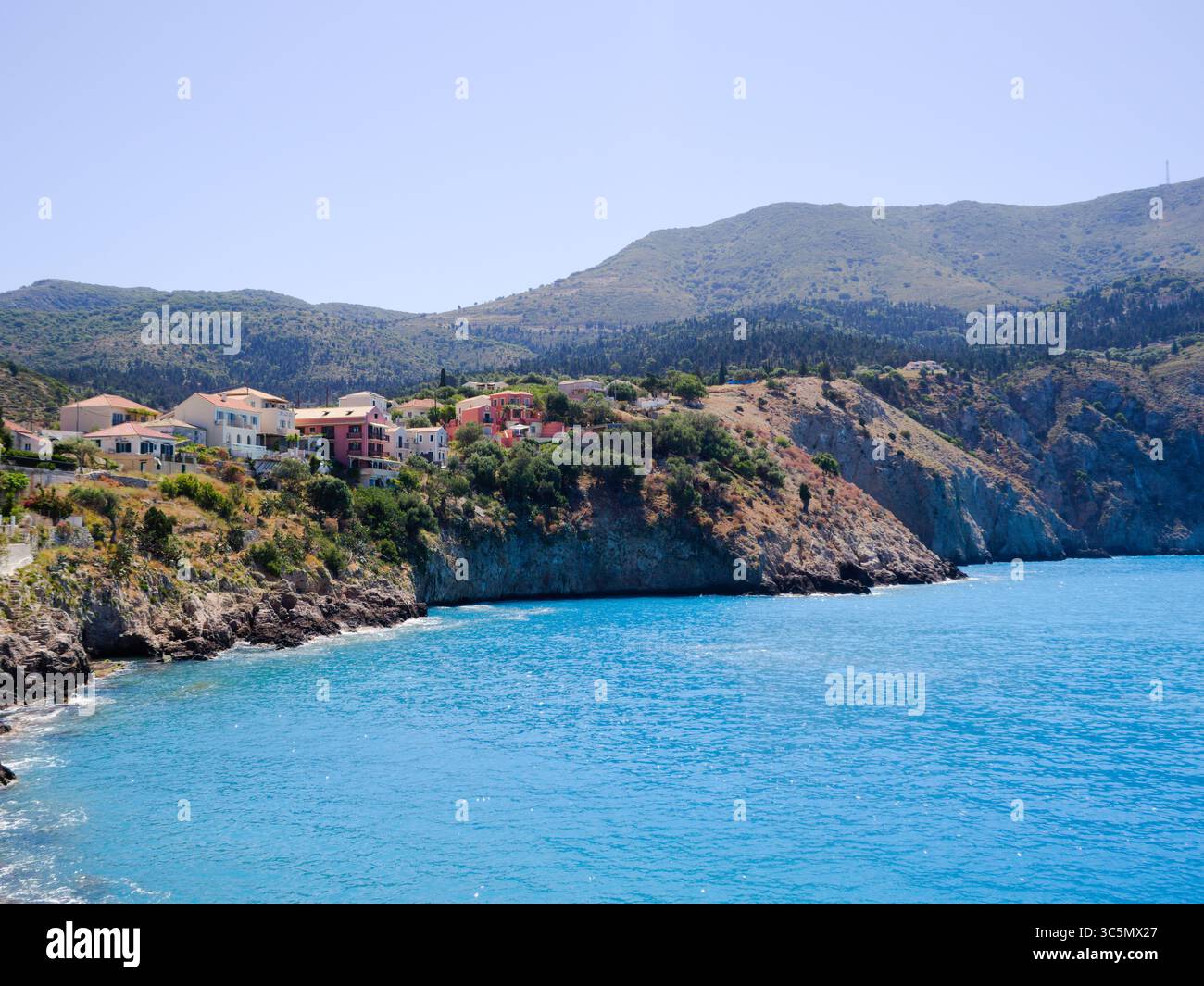 L'iconica Assos a Cefalonia con un porto tranquillo, edifici vibranti e un'atmosfera estiva. Foto Stock