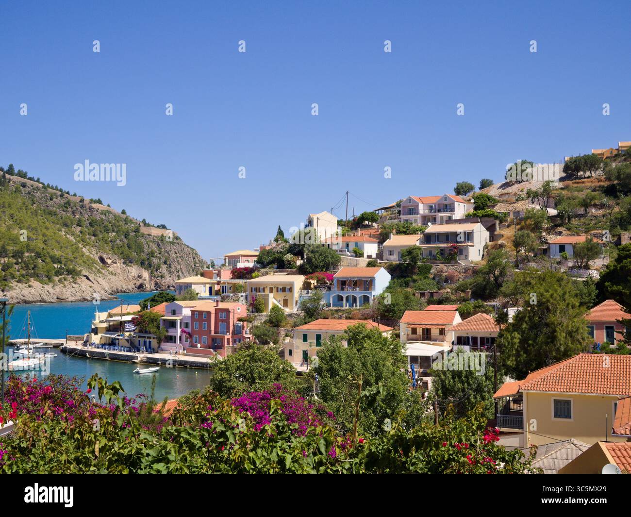 Villaggio di Assos sull'isola di Cefalonia, in Grecia, con case colorate e mare turchese in una soleggiata giornata mediterranea. Foto Stock