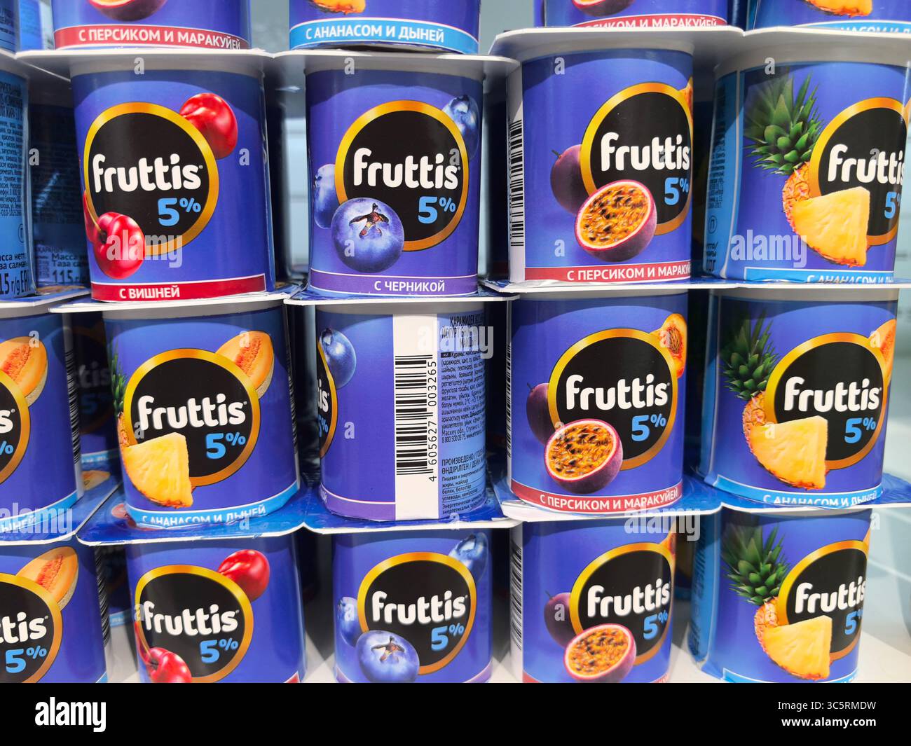 Babruisk, Bielorussia - 16 giugno 2025: Tazze di yogurt colorate impilate ordinatamente in un corridoio di alimentari che mostrano vari sapori di frutta. Foto Stock