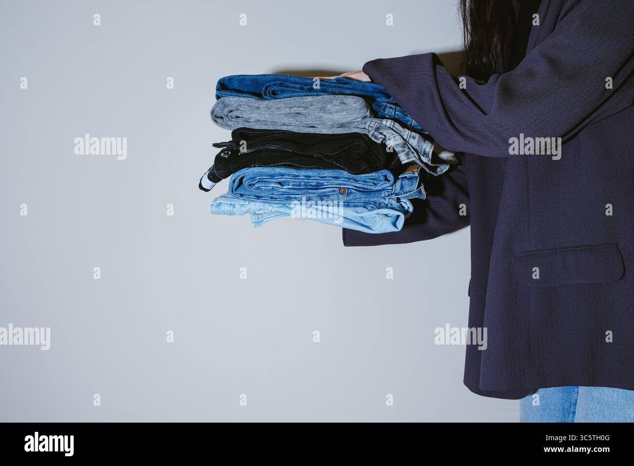 Donna che tiene i jeans sullo sfondo leggero Foto Stock
