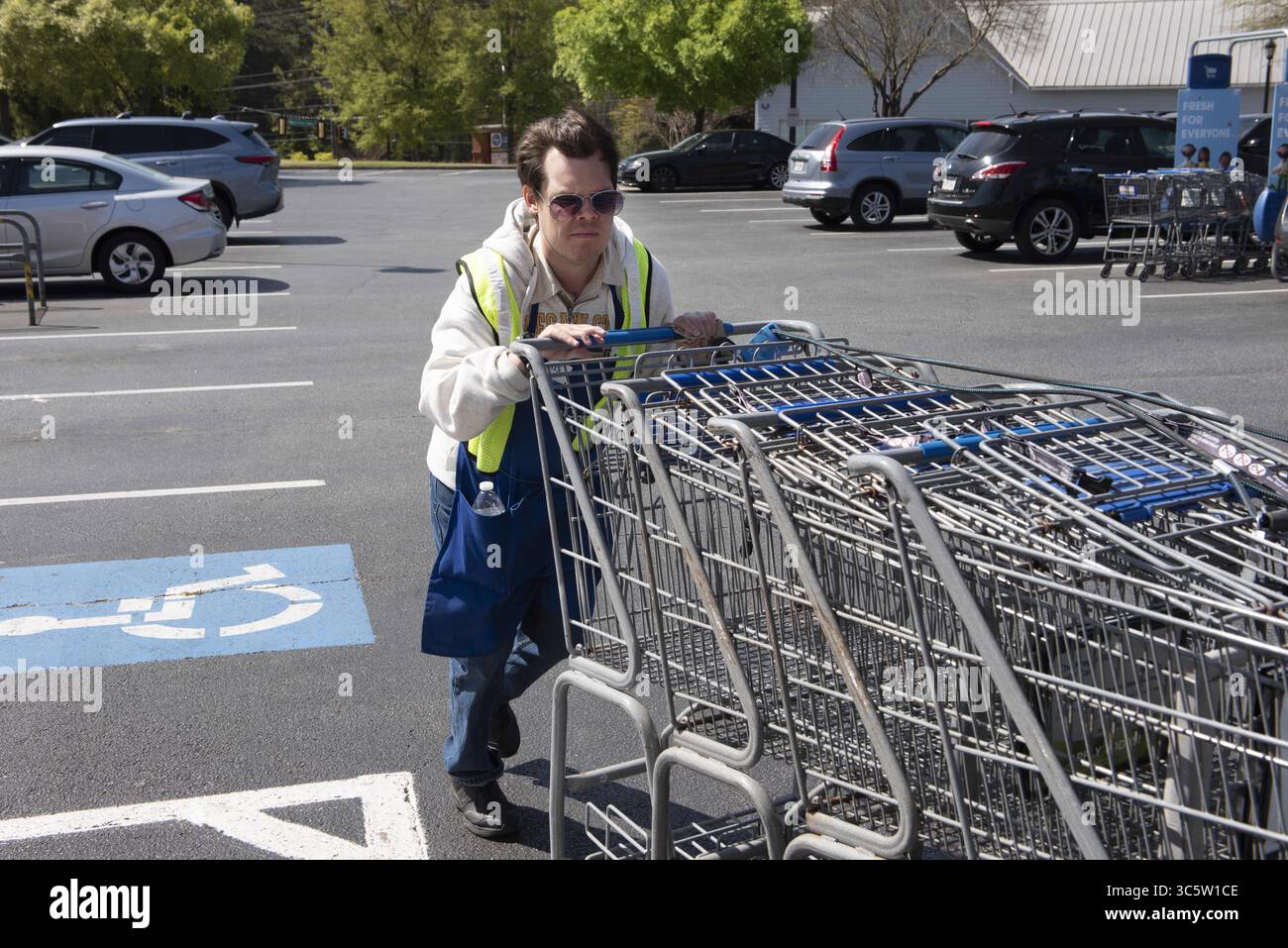 2 aprile 2020, Canton, GA, Stati Uniti: Chris Nelson, 36, che ha una disabilità dello sviluppo, raccoglie i carrelli fuori da un supermercato Kroger dove heÃs ha lavorato part-time per più di un anno. È considerato un Ã”essenziale workerÃ perché è impiegato in un negozio di alimentari, ed è attento a pulire i carrelli con disinfettanti quando li riporta al negozio. (Immagine di credito: © Robin Rayne/ZUMA Wire) Foto Stock