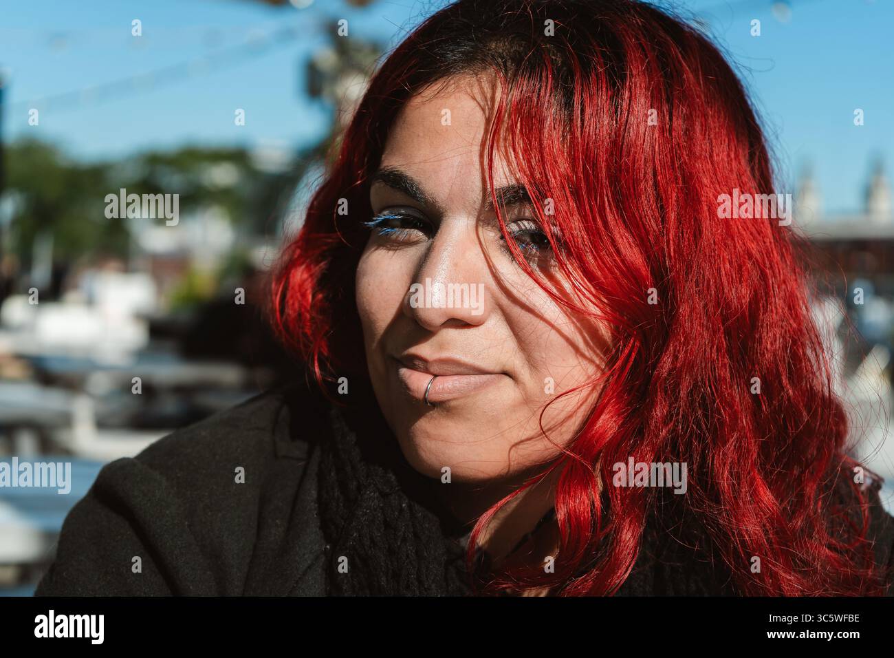 Ritratto di una giovane donna fresca con i capelli rossi brillanti e un labbro piercing che si gode una giornata di sole all'aperto Foto Stock
