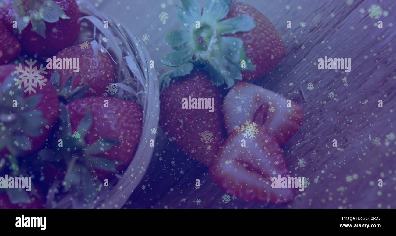 Esporre una ciotola di vetro traboccante di fragole intere tagliate a fette sul tavolo della cucina, con fiocchi di neve Foto Stock