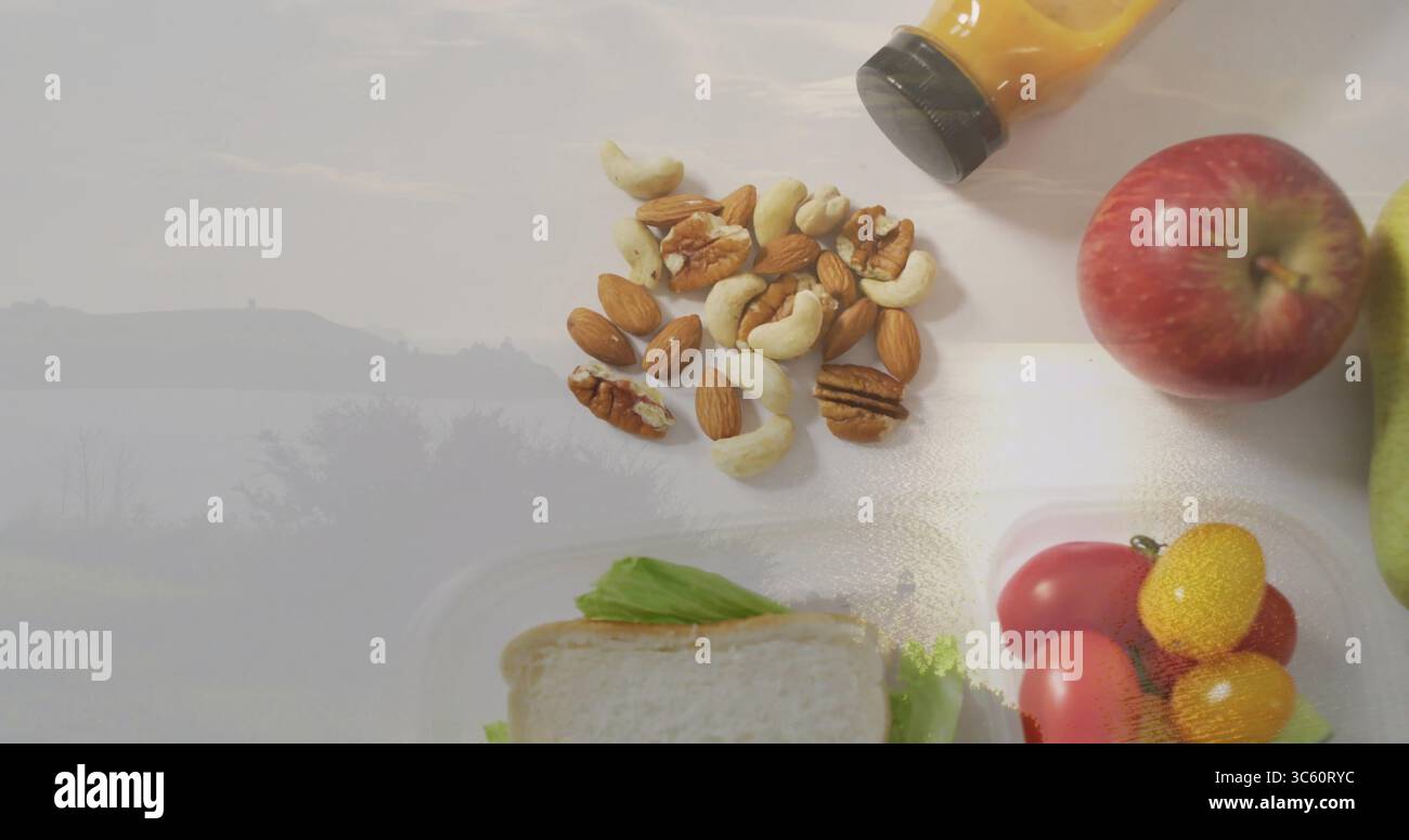 Disporre il composto di noci su un piano di lavoro bianco con scatola per sandwich, pomodori ciliegini, bottiglia di succo, mela, pera Foto Stock