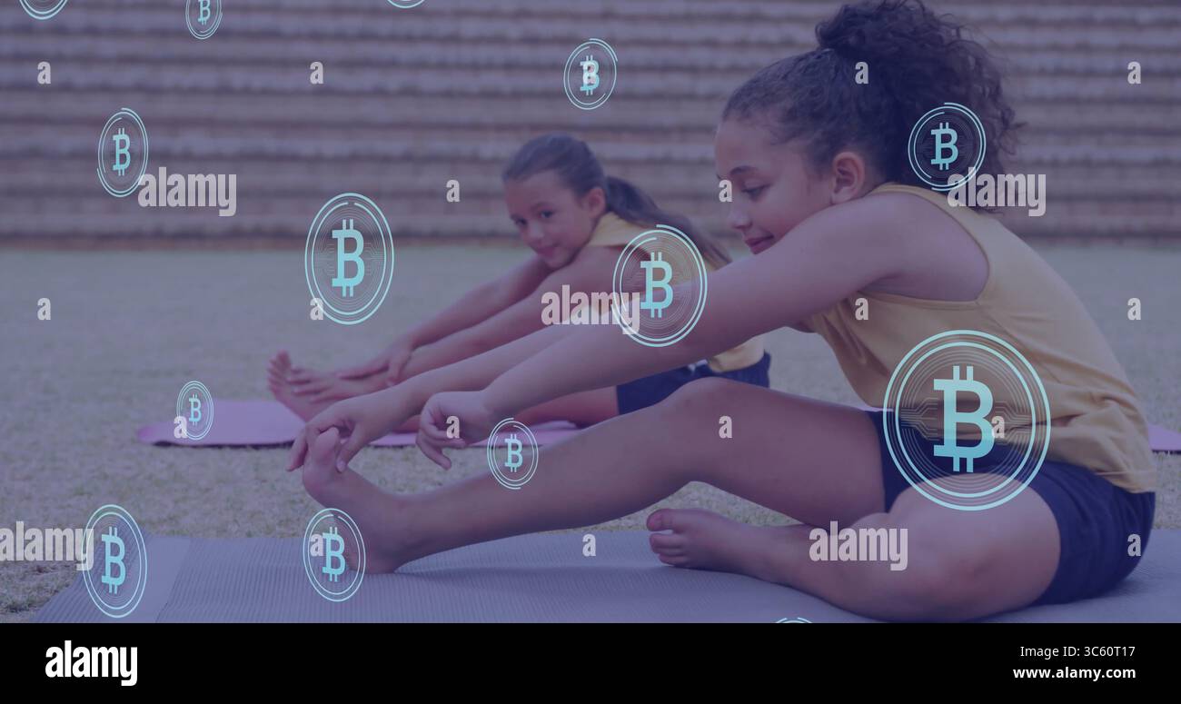 Raggiungere il bambino con le dita dei piedi toccando a destra sui tappetini da yoga sul campo erboso, con le icone Bitcoin fluttuanti Foto Stock