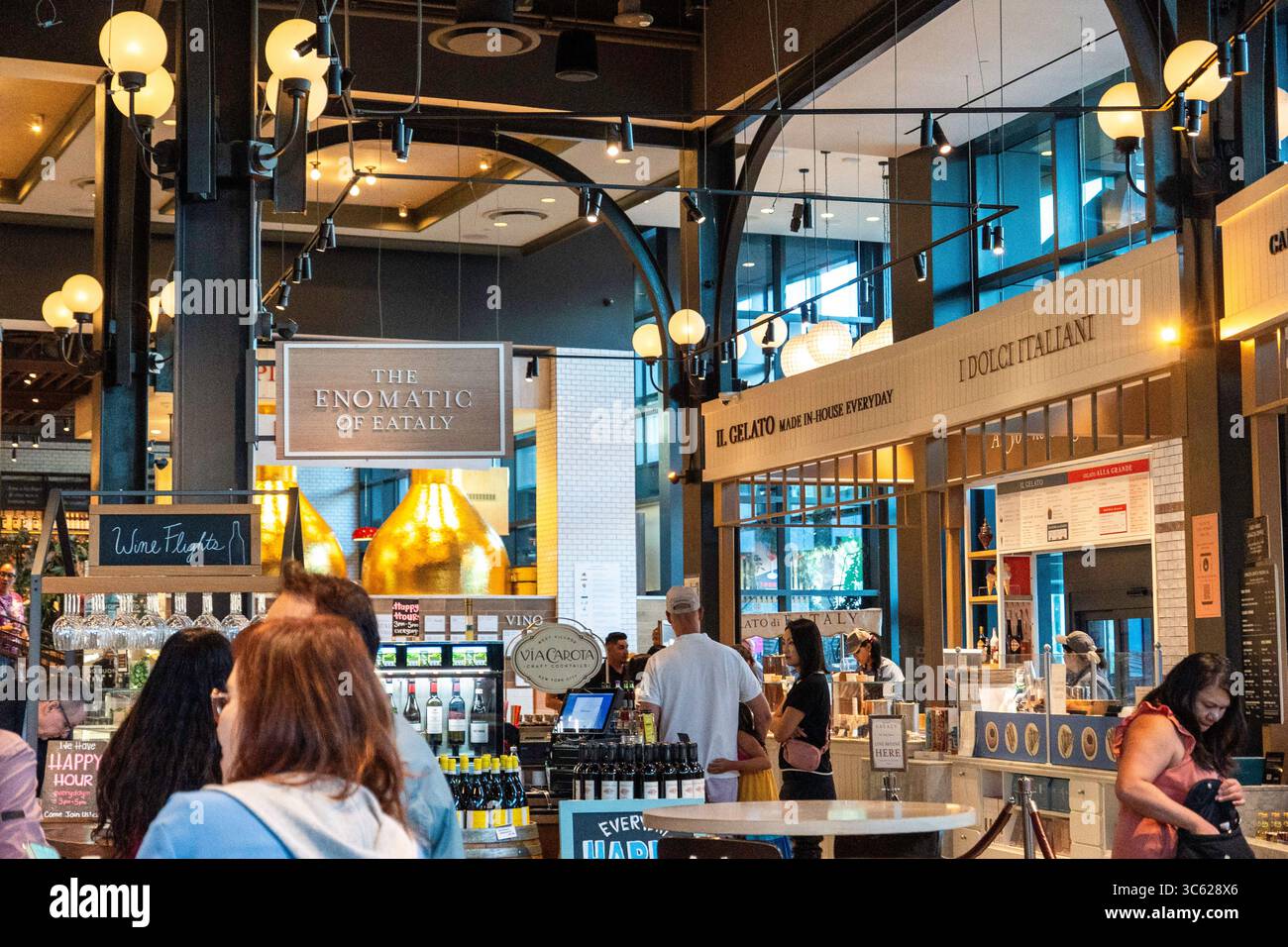 Un gruppo di persone sta attualmente in piedi e conversando in un vivace ambiente ristorante, circondato da vari elementi di design Foto Stock