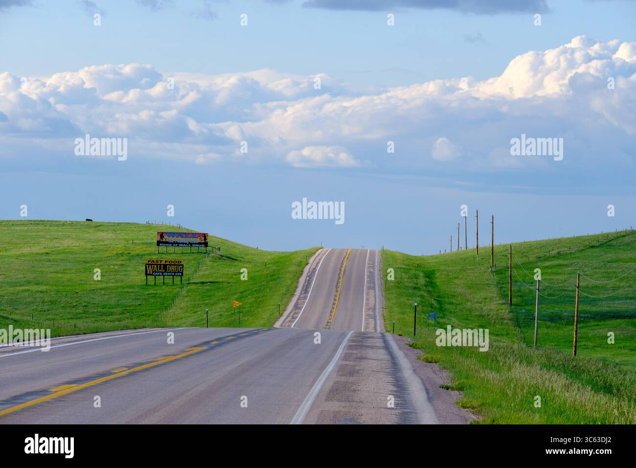 Un'autostrada solitaria in primavera con cartelloni pubblicitari Wall Drug e nuvole di tempesta lontane, che catturano la cultura stradale e i paesaggi aperti della Midw americana Foto Stock