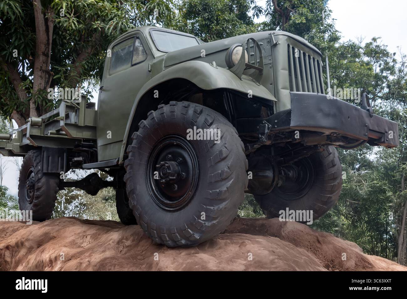 Camion militare verde parcheggiato su terra in un'area boscosa Foto Stock