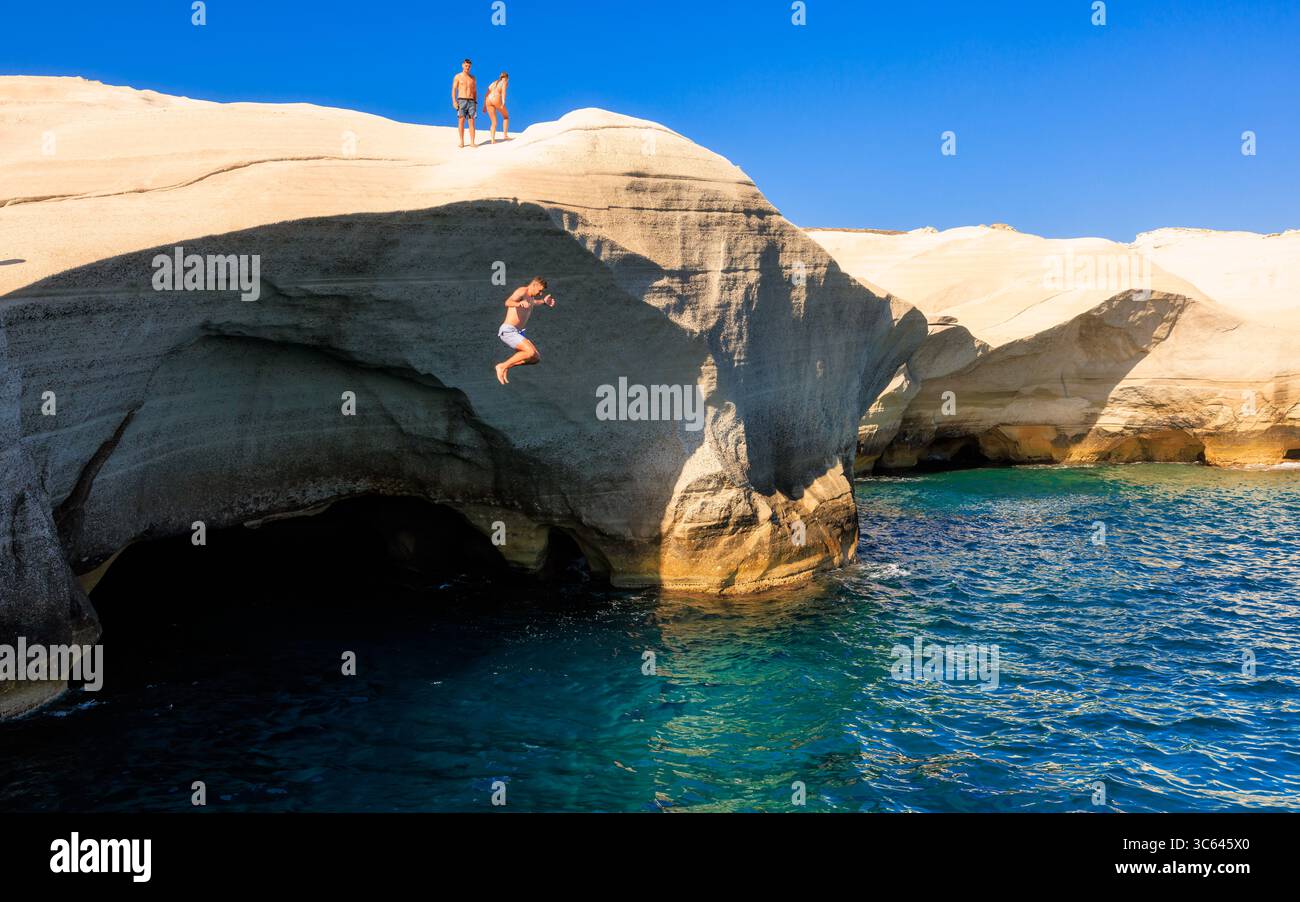 Donna che salta dalla scogliera al mare alla spiaggia di Sarakiniko, Milos, Grecia Foto Stock