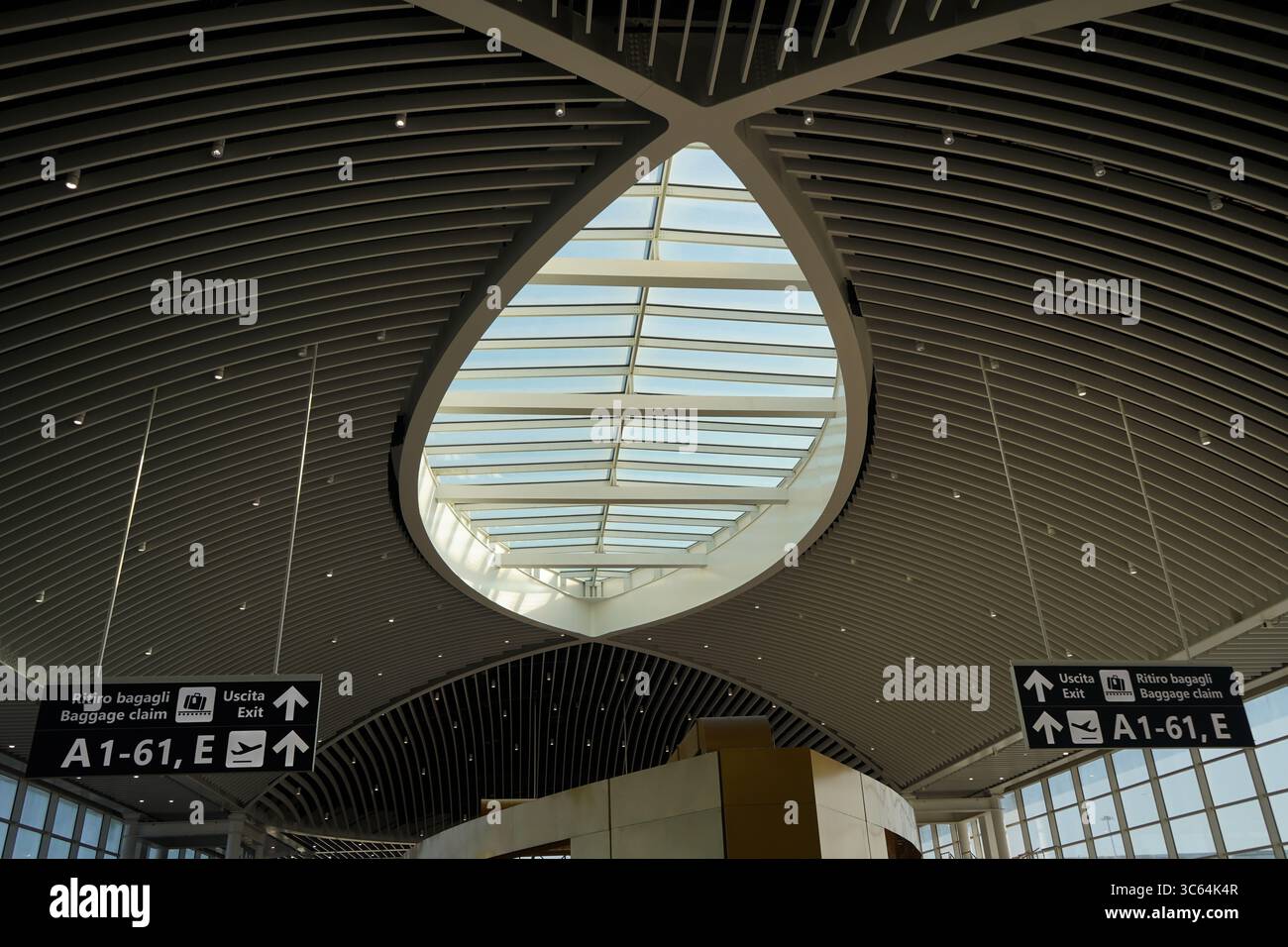 Un moderno terminal dell'aeroporto di Fiumicino con lucernario ovale in vetro. Due cartelli sotto il lucernario indicano "ritiro bagagli". Foto Stock