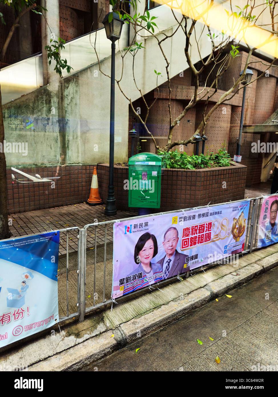 Banner della campagna politica di Hong Kong Street con ritratti dei candidati sul recinto urbano del marciapiede durante la stagione elettorale Foto Stock