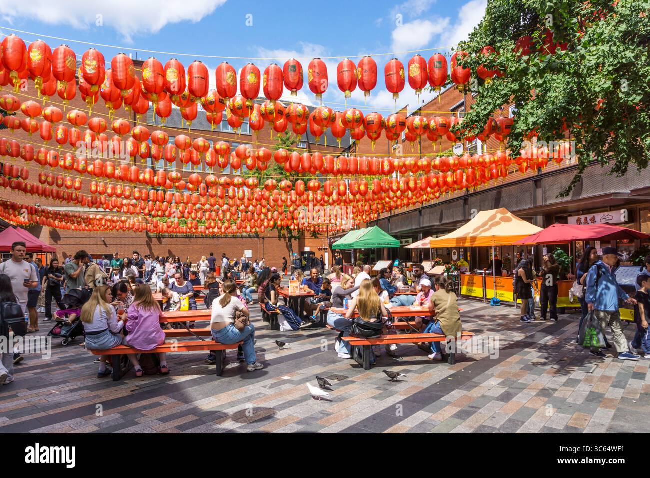 Gente che mangia fuori sotto le lanterne cinesi a Newport Place, Soho. Foto Stock