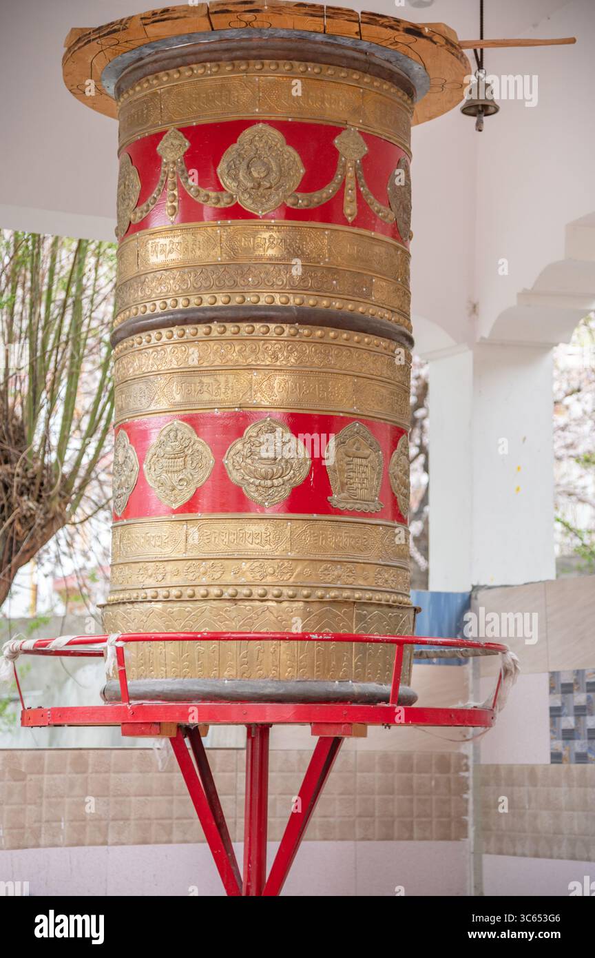 Tradizionale ruota di preghiera buddista fuori da un monastero, simbolo di fede e spiritualità, utilizzata per la meditazione e il canto dei mantra. Foto Stock