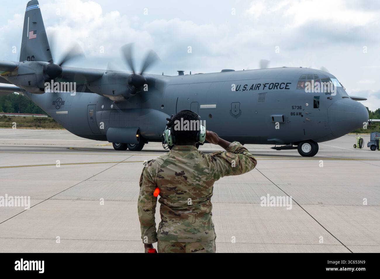 Un US Airman assegnato al 86th Aircraft Maintenance Squadron rende omaggio a un C-130J Super Hercules in partenza alla Ramstein Air base, Germania, Foto Stock