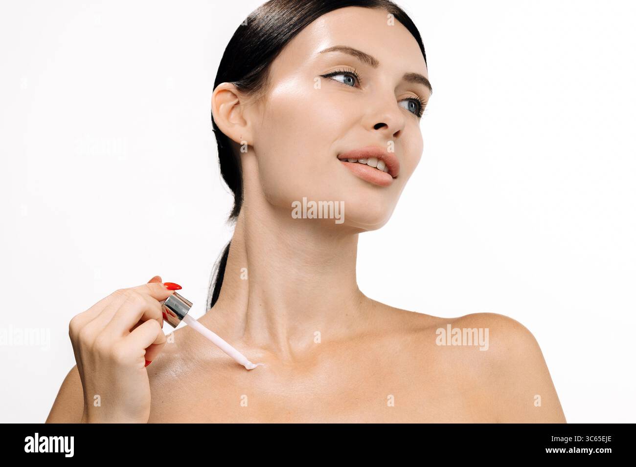 Donna applica siero ringiovanente al collo, mettendo in risalto la pelle liscia e il bagliore naturale, su uno sfondo minimalista che esalta il bea Foto Stock