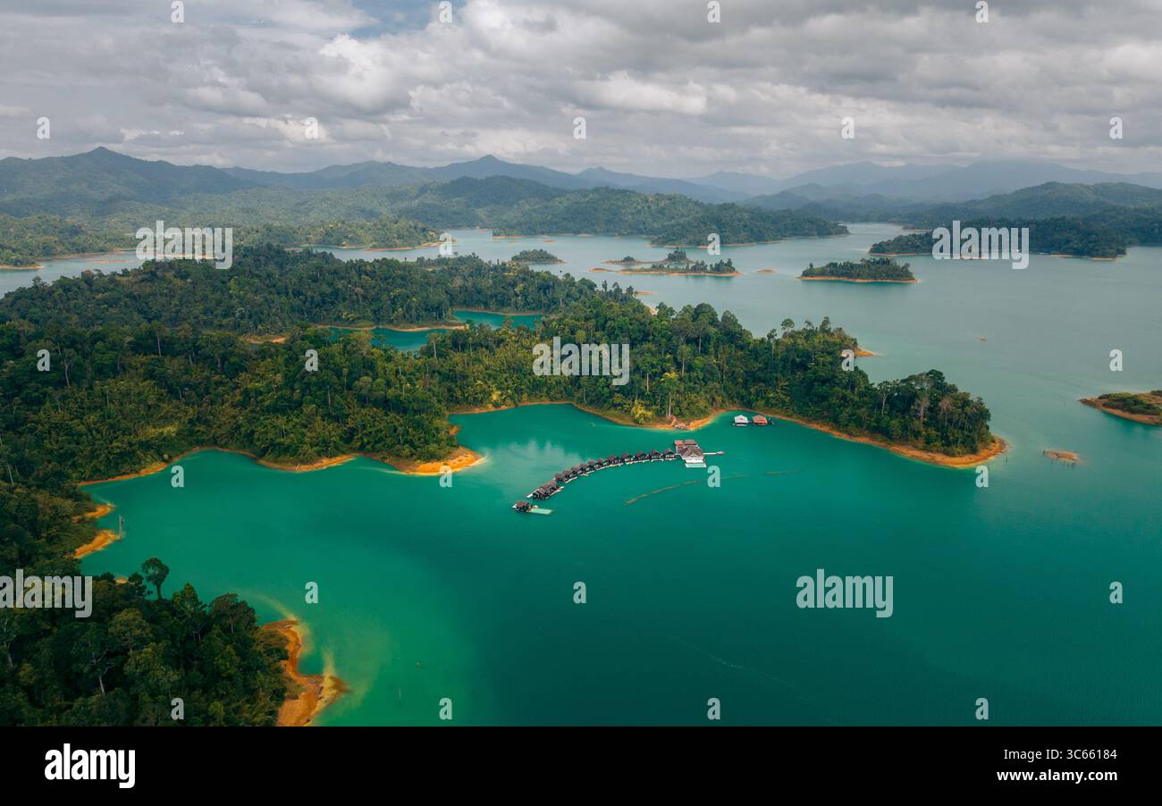 Vista aerea delle acque verdi di giada che abbracciano le isole verdeggianti sotto un vasto cielo, creando un incredibile contrasto di colori e texture, Khao Sok, Thailandia. Foto Stock