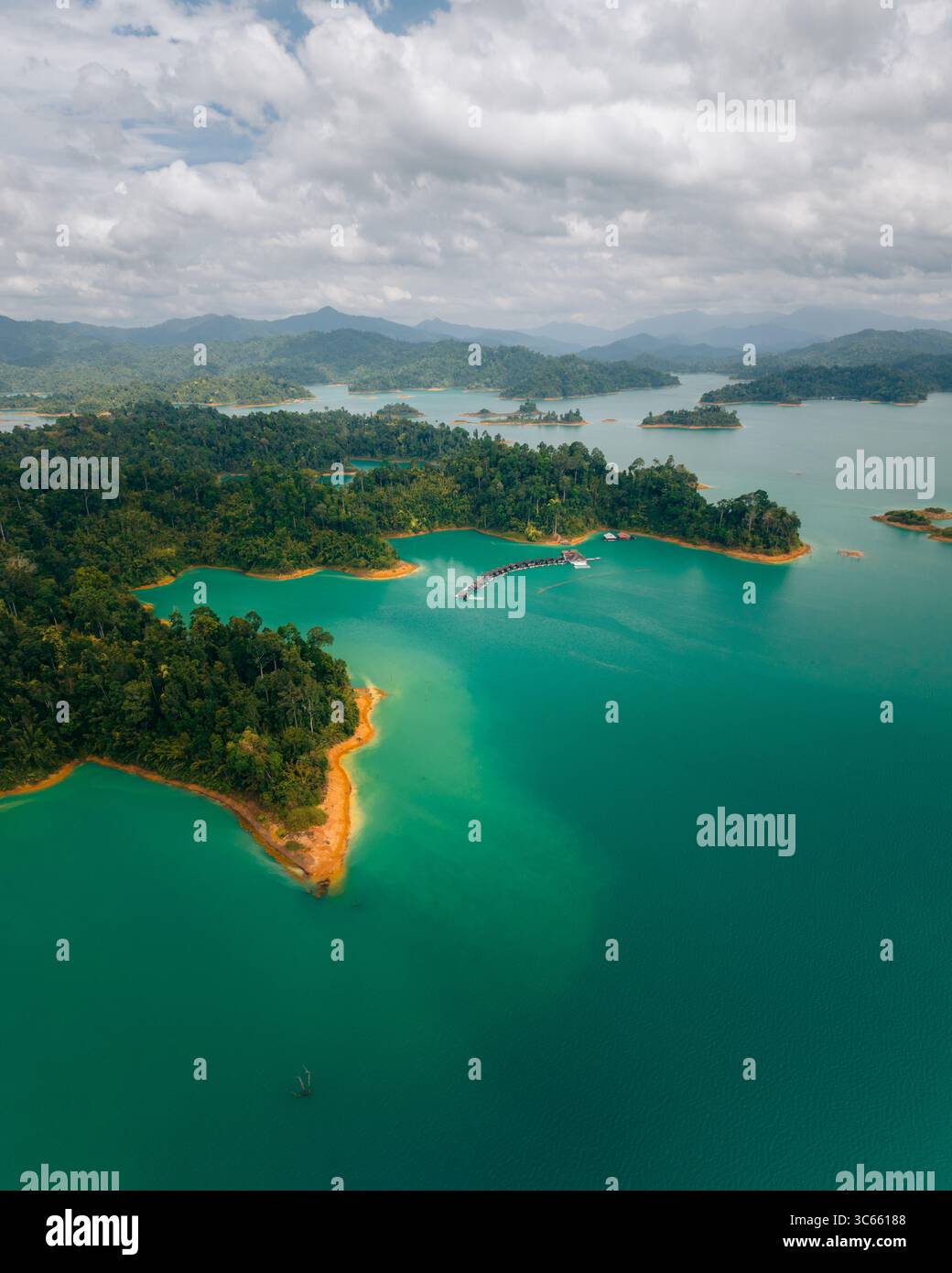 Vista aerea delle acque color smeraldo che abbracciano lussureggianti isole boscose sotto un vasto cielo, creando un vibrante contrasto della tavolozza della natura, il Parco Nazionale di Khao Sok, Surat Thani, Thailandia. Foto Stock