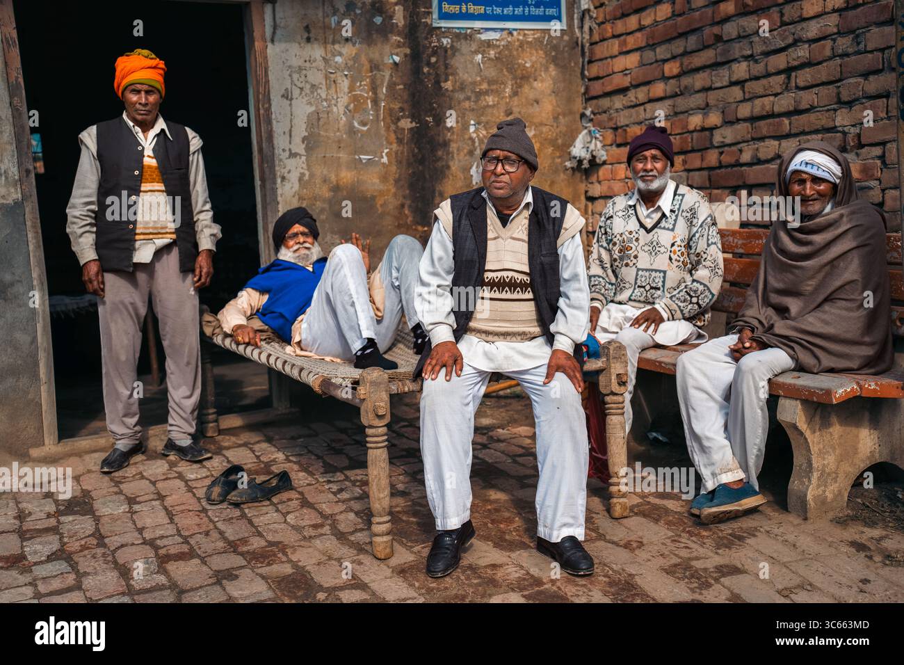 Kolkata, India - 28 gennaio 2023: Veduta di un gruppo di uomini riuniti in un momento sincero fuori da un edificio tradizionale, il loro abbigliamento e le loro espressioni diverse dipingono un vivido ritratto della vita quotidiana. Foto Stock