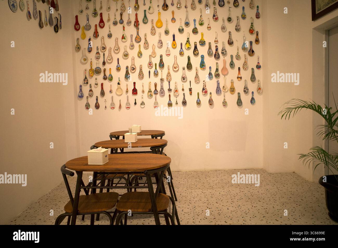 Una collezione di colorati cucchiai antichi di vari paesi, esposti su una parete in una stanza. Foto Stock