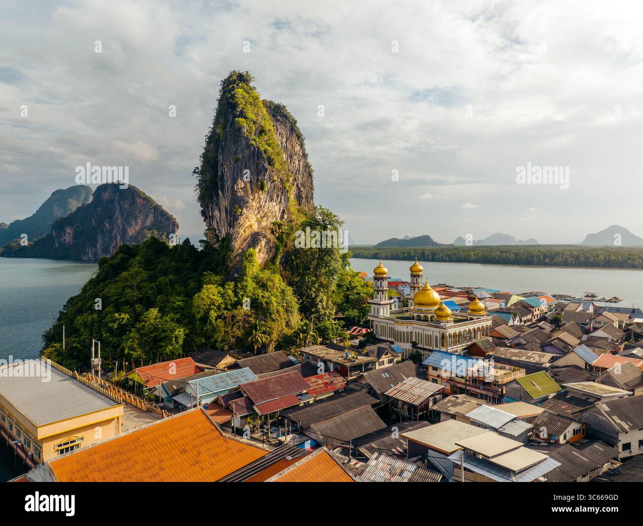 Vista aerea di una moschea dalla cupola dorata annidata tra i vivaci e rustici tetti di Koh Panyi, con torreggianti scogliere calcaree che si innalzano maestosamente dal mare turchese, Ko Panyi, Phang Nga, Thailandia. Foto Stock