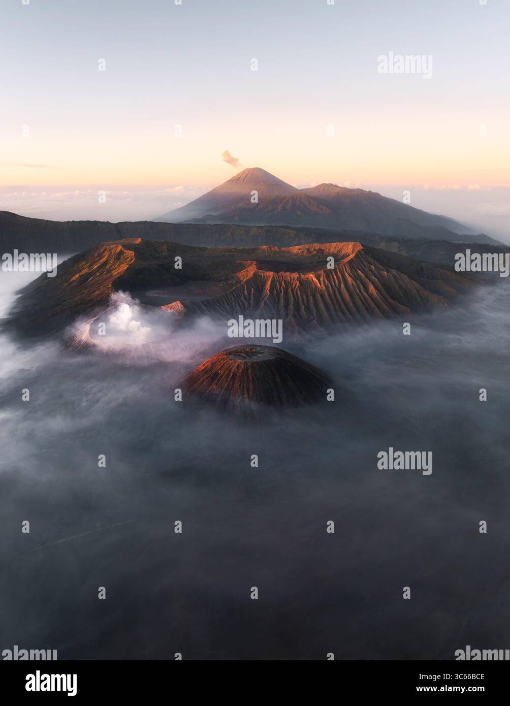 Vista aerea del maestoso Monte Bromo avvolto da una nebbia eterea, le sue vette vulcaniche che piergono l'alba, creando un paesaggio spettacolare, il Parco Nazionale di Bromo Tengger Semeru, Giava Orientale, Indonesia. Foto Stock
