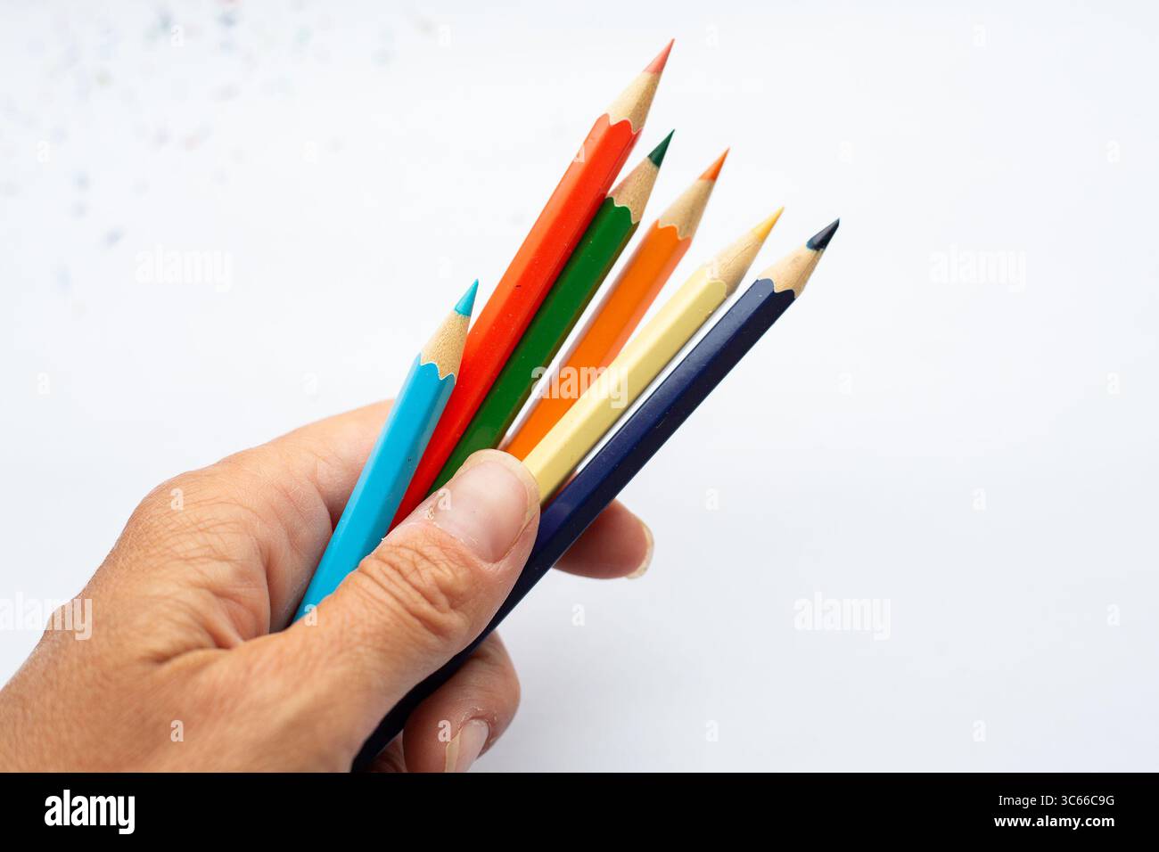 Una persona ha in mano un mazzo di matite vibranti e colorate Foto Stock