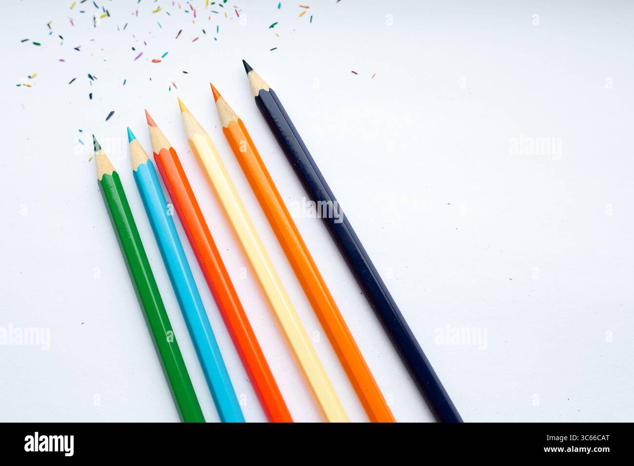 Una fila ordinata di matite colorate è allineata su una superficie bianca Foto Stock