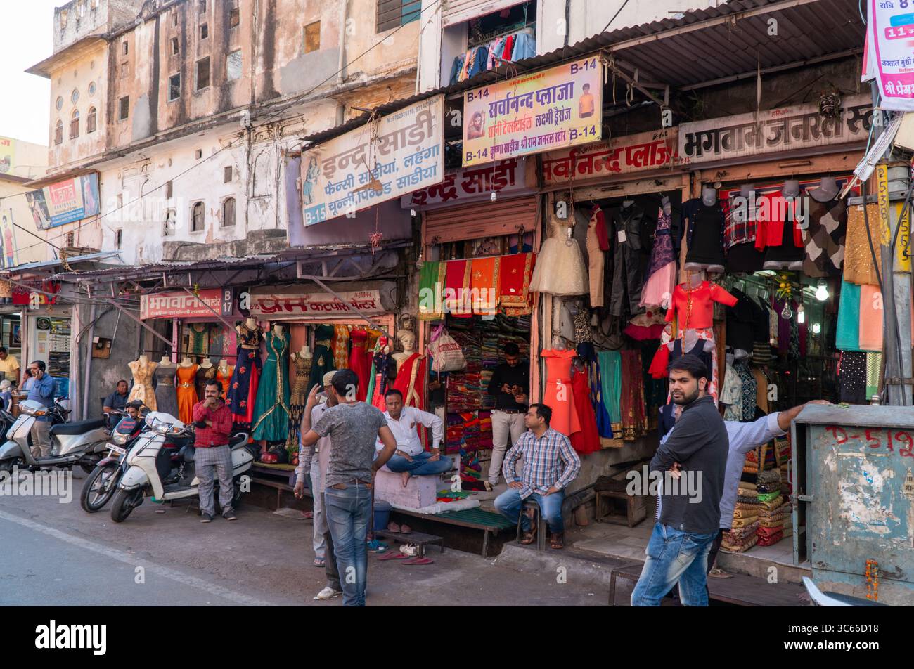 Una vivace e vivace scena di strada indiana nell'area del mercato di Bikaner, Rajasthan, India. I vari negozi vendono tessuti e abbigliamento. Foto Stock