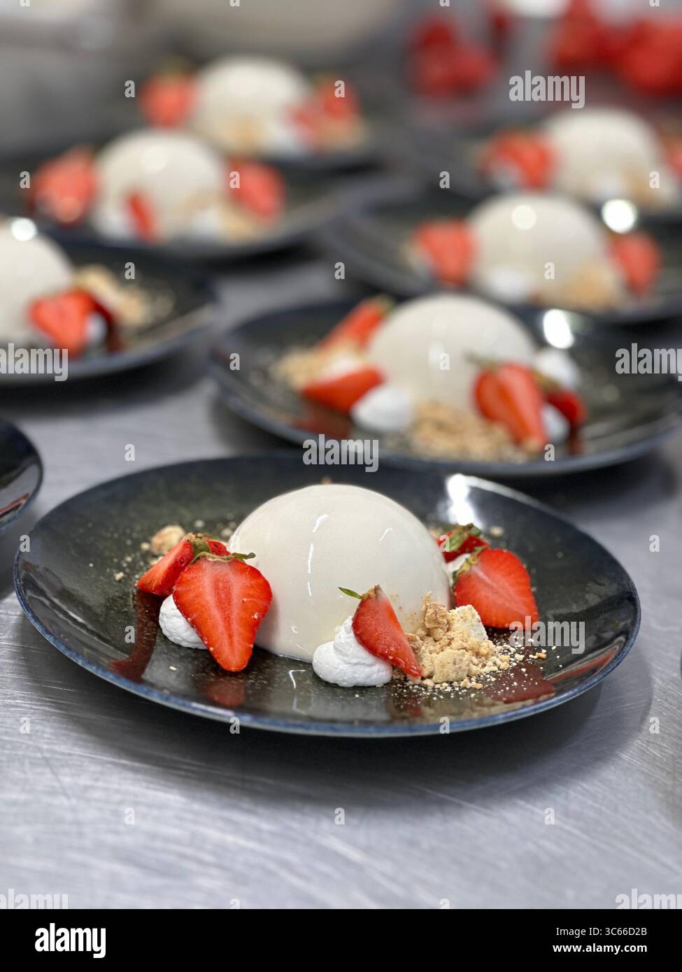 Panna cotta con fragole fresche su un piatto nero da vicino Foto Stock