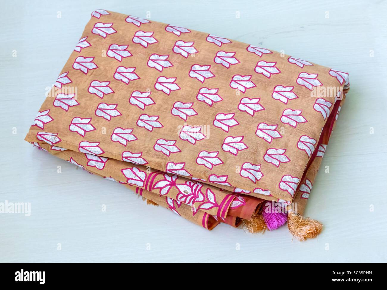 Un bellissimo sari in cotone stampato con motivi floreali su una superficie in legno chiaro. I sari sono un indumento senza tempo, spesso indossato dalle donne del Bangladesh per celebrare lo speciale Foto Stock