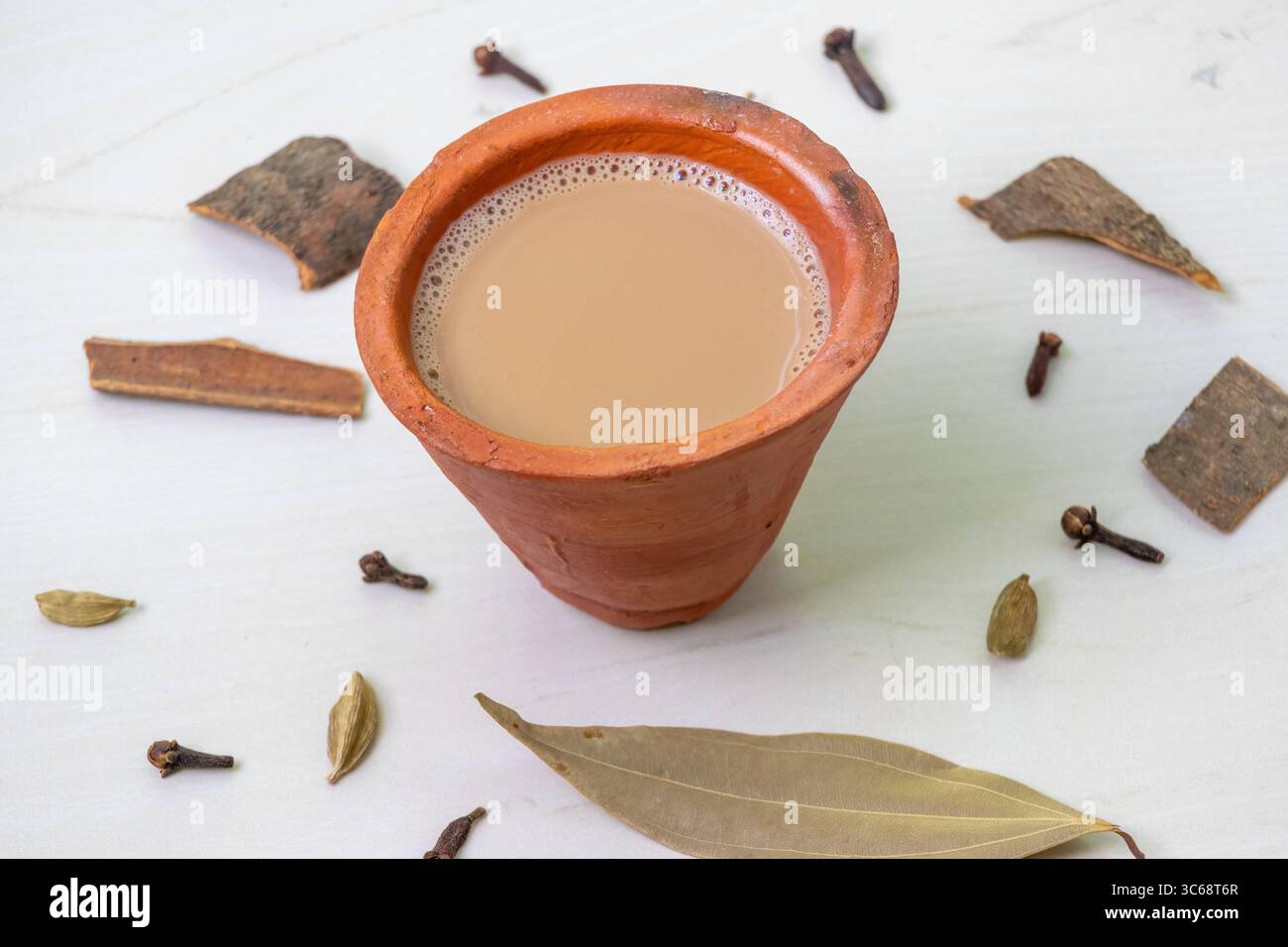 Una tazza di tè masala caldo, o Kadak Chai indiano, servito in una tazza di argilla su una superficie di legno. Foto Stock