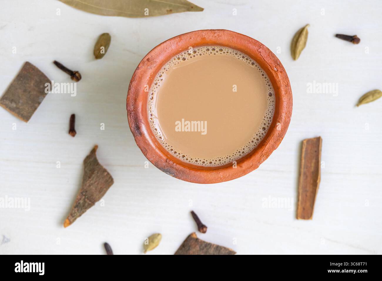 Vista dall'alto di una tazza di tè masala caldo, o Kadak Chai indiano, servito in una tazza di argilla su una superficie di legno. Foto Stock