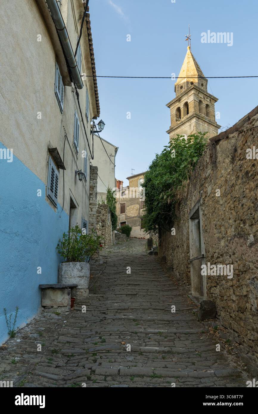 Affascinante strada stretta lastricata di antiche pietre nella cittadina medievale collinare di Motovun, Istria, Croazia. Idilliaco ambiente europeo, perfetto per i viaggi e per chi viaggia Foto Stock